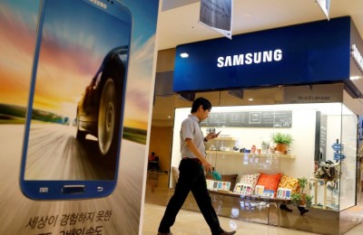A man using his mobile phone walks past a Samsung Electronics shop in the company's main office building in central Seoul July 23, 2013. Samsung Electronics Co Ltd is under mounting pressure to produce eye-catching new smartphones after its mobile business shrank 3.5 percent in the second quarter, taking the gloss off a record $8.5 billion operating profit. Picture taken July 23.     REUTERS/Lee Jae-Won (SOUTH KOREA - Tags: BUSINESS LOGO)