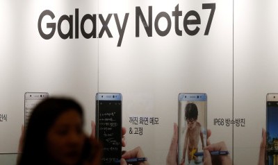 A woman talking on her mobile phone walks past an advertisement promoting Samsung Electronics' Galaxy Note 7 at company's headquarters in Seoul